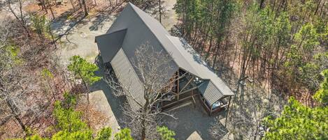 A cabin with a sloped roof surrounded by dense forest.