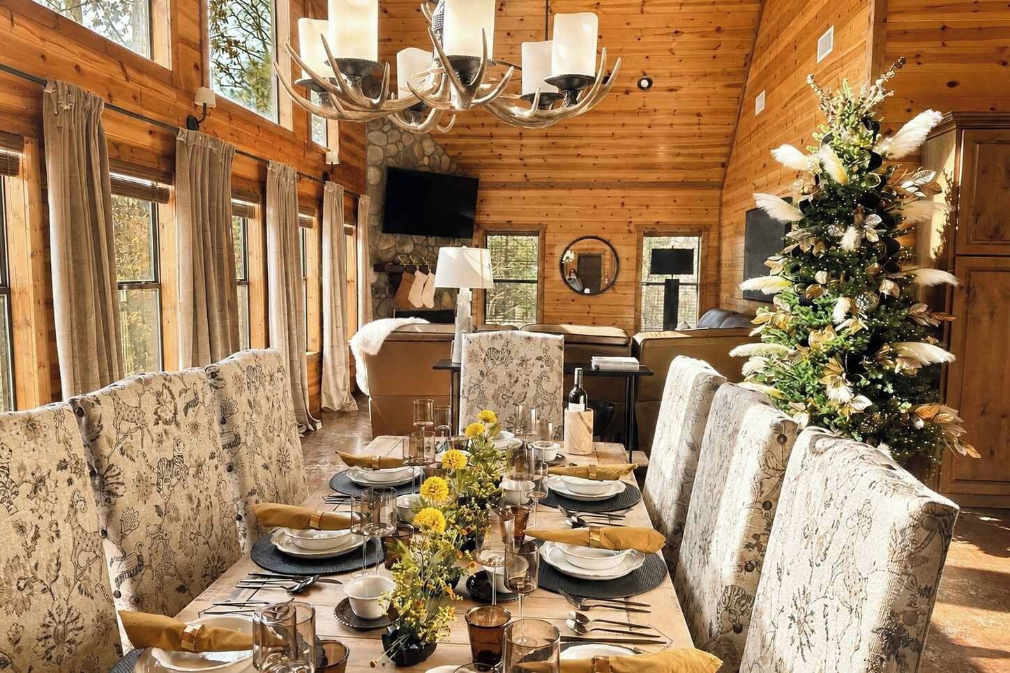 A dining area with a long table set for a meal, surrounded by upholstered chairs with floral patterns.