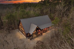 A log cabin with a large porch, surrounded by dense forest. - As Seen on TV! Safari Views + Hot Tub + Firepit (Broken Bow)