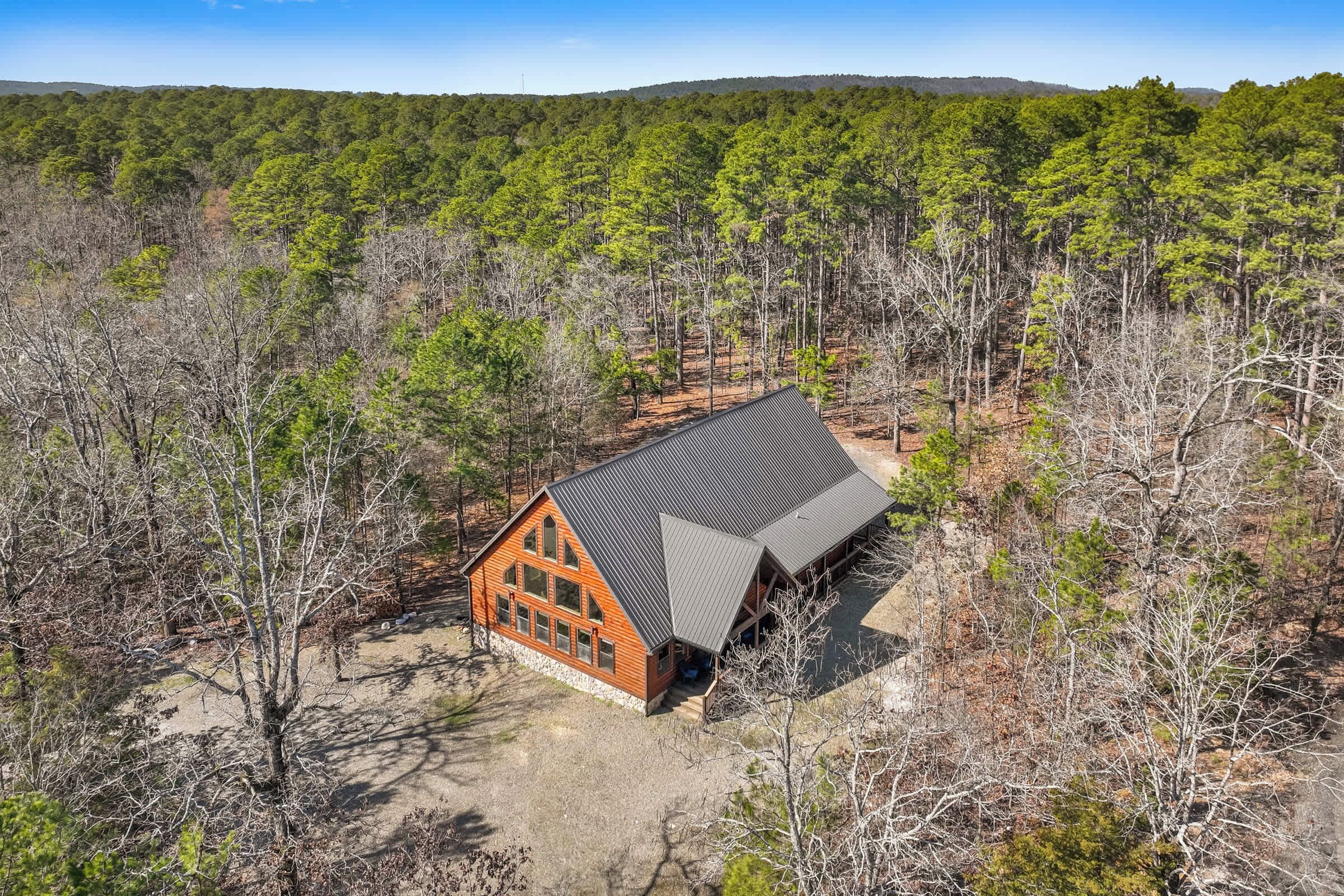 Une cabane avec un toit en pente, entourée d’une forêt.