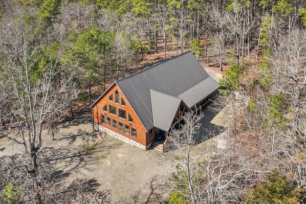 A cabin with a sloped roof, surrounded by trees.