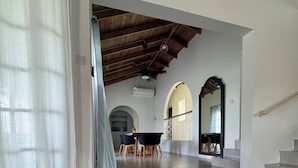 Una habitación amplia con techo alto, un comedor con mesa y sillas, y una escalera que conduce a un nivel superior.