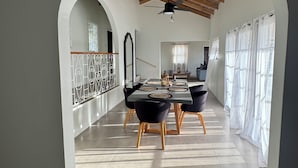 Un comedor de concepto abierto con techo alto y vigas de madera, una mesa de comedor con sillas y vistas a otra habitación a través de un arco.