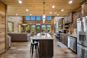 A spacious kitchen with a central island, wooden cabinetry, and a large refrigerator.