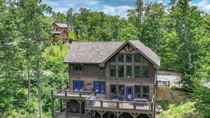 Une cabane en bois à plusieurs étages, dotée de balcons et entourée d’une forêt dense.