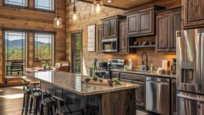 Une cuisine spacieuse dotée d’un grand îlot central, d’appareils électroménagers en acier inoxydable et de meubles de rangement en bois.