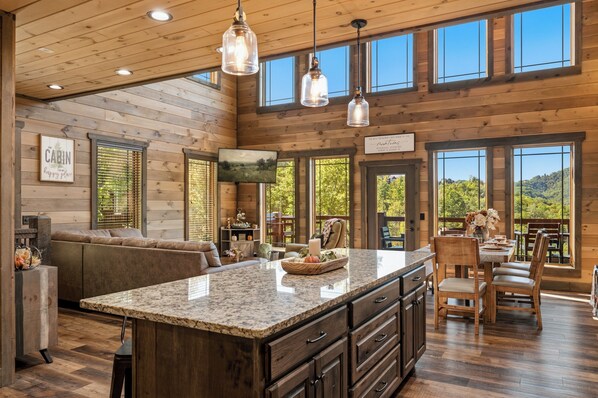 A spacious kitchen with a large island, wooden cabinetry, and a view of the outdoors.