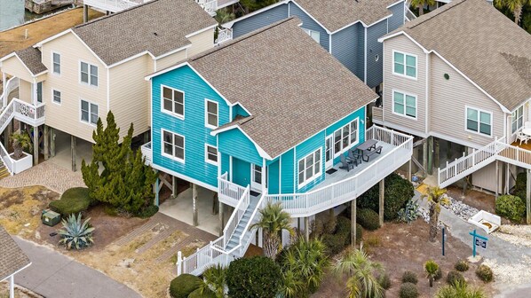 A multi-story house with a blue exterior, a covered porch, and a staircase leading to the upper floor.