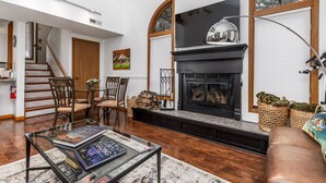 A spacious living room with a fireplace, a glass coffee table, and a staircase leading to an upper level. - Unwind at Star Gazer`s Getaway (Galena)