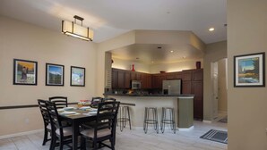 A modern kitchen with dark wooden cabinets, a central island with stools, and a dining area with a table and chairs. - The Old Mill Retreat Sleeps 6! (Bend)