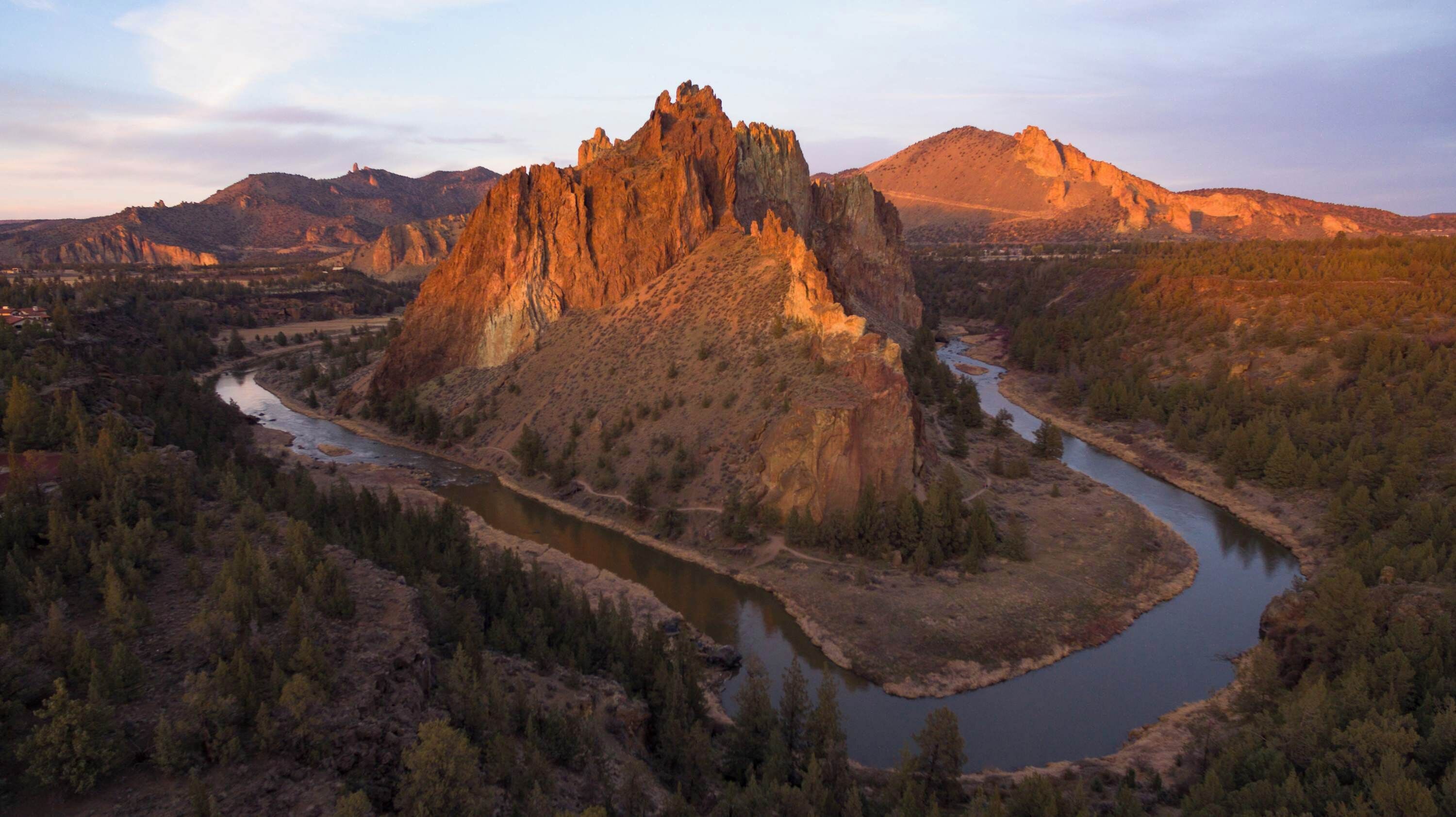 A mountainous landscape with a river winding through a forested valley.