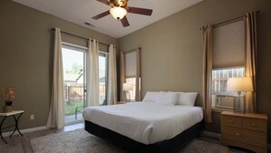 A bedroom with a large bed, a ceiling fan, a nightstand, and a window with blinds. - The Old Mill Retreat Sleeps 6! (Bend)
