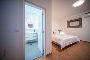A bedroom with a bed, a bedside table, a nightstand, a window with a wooden frame, and a wall-mounted mirror. - Quinta Da Victória By Venimar (Viana do Castelo)