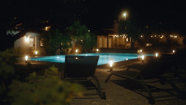 A nighttime pool area with lounge chairs and candles. - Quinta Da Victória By Venimar (Viana do Castelo)