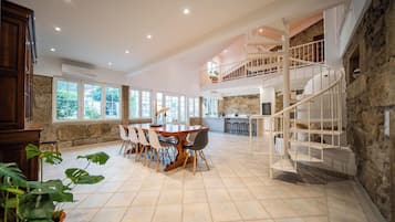 A spacious dining area with a high ceiling and a view of the outdoors through large windows.