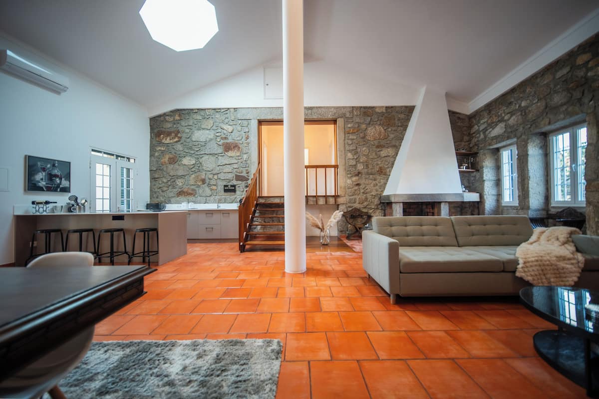 A spacious living area with a stone wall, a sofa, and a dining table.