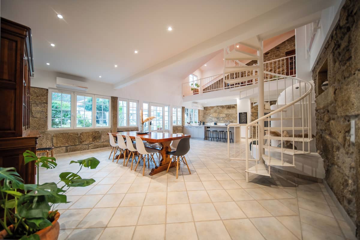 A spacious kitchen with a dining area, a staircase, and a stone wall.