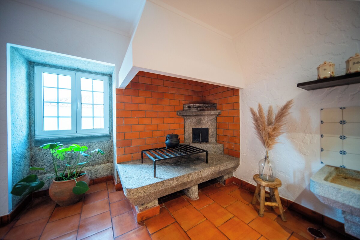 A kitchen with a brick wall, a stone bench, a window, and a potted plant.