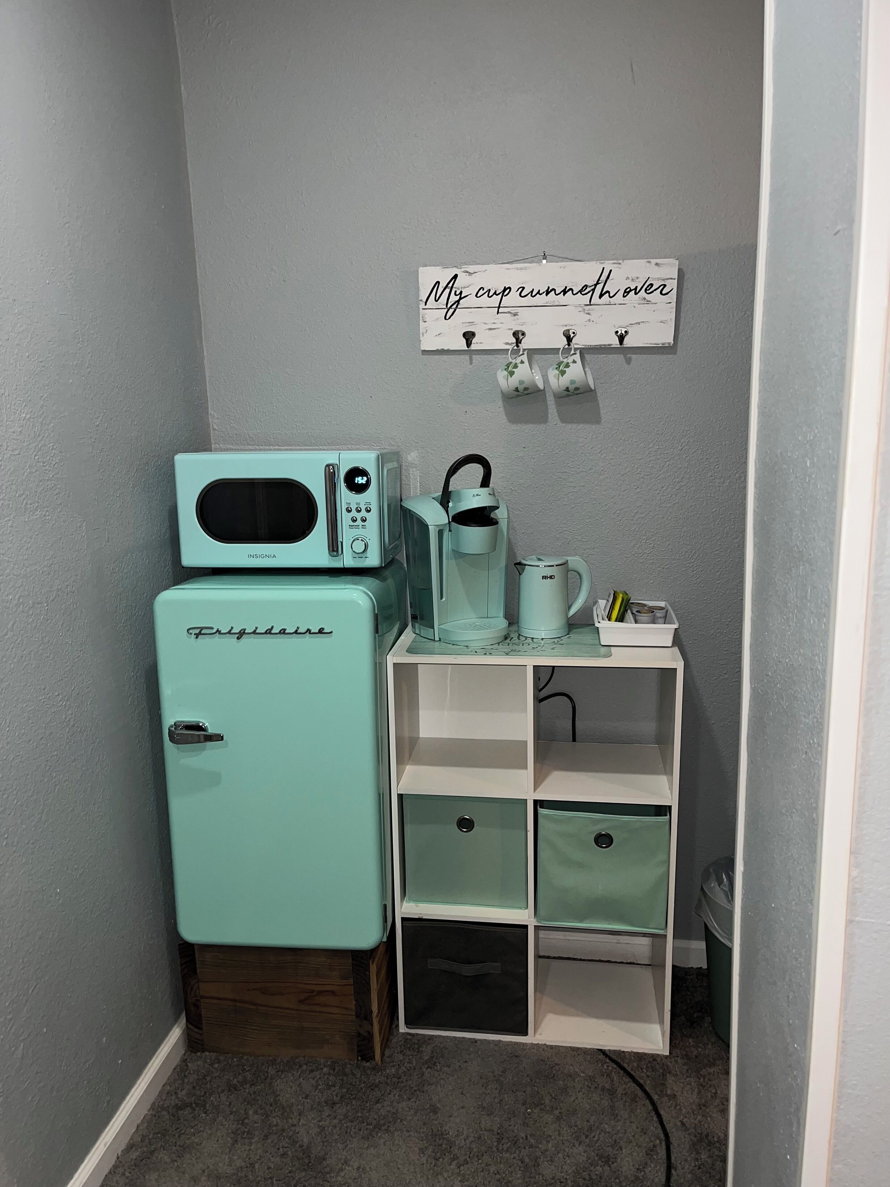Una kitchenette compacta con refrigerador, microondas y cafetera.