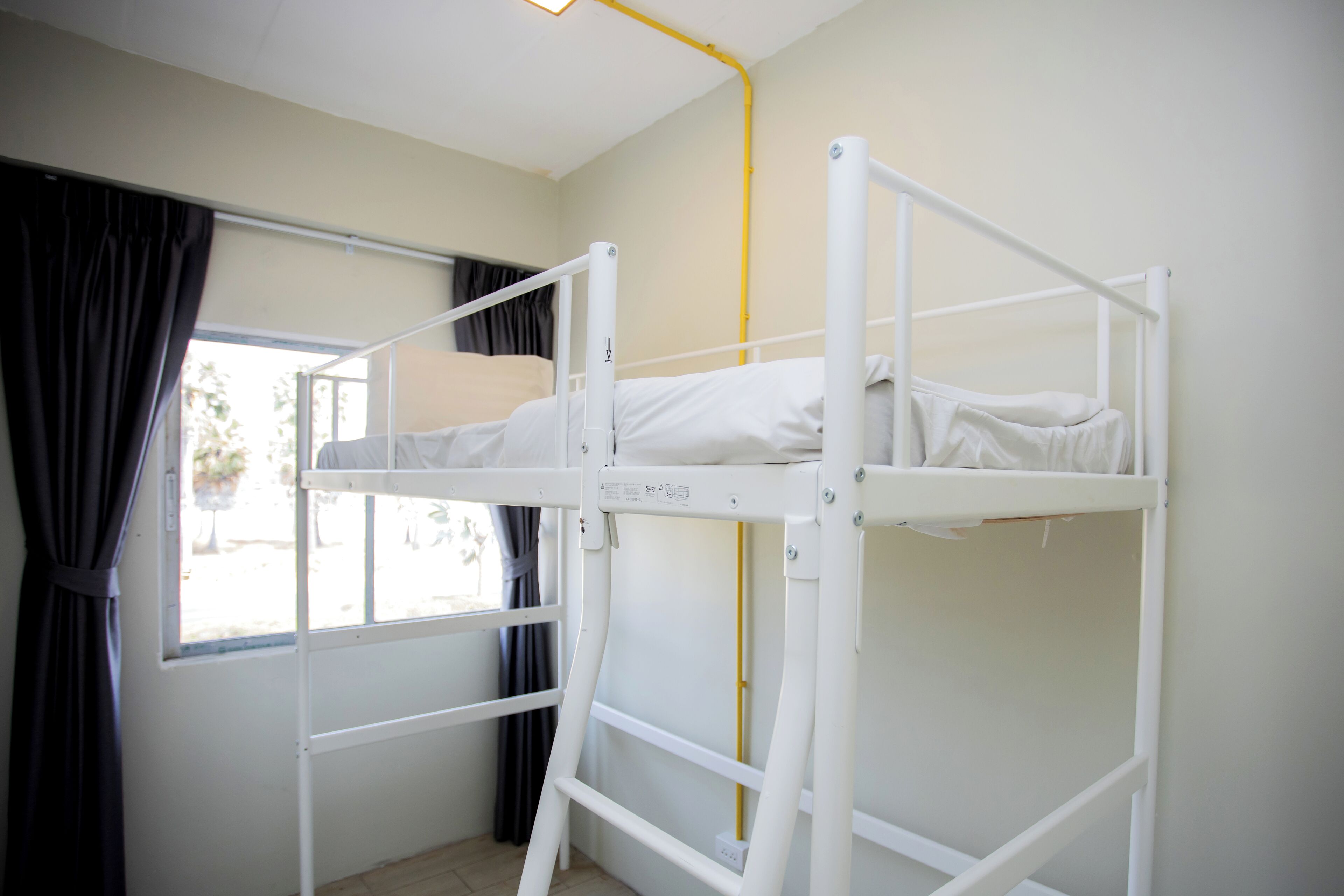 A bunk bed room with a window and curtains.