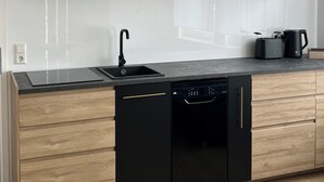 Une cuisine moderne avec des meubles en bois, un lave-vaisselle noir et un four encastré.