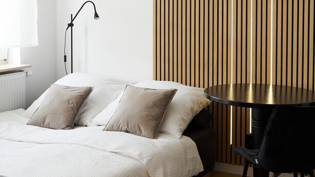 Une chambre à coucher moderne avec un lit, une table de chevet, une lampe et une table ronde accompagnée d’une chaise.