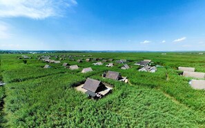 A rural area with numerous small, thatched-roof houses scattered across a green field. - Mountains&Lakes - Romantika5 Rust (Rust)