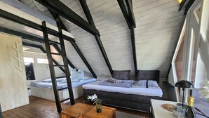 A loft-style bedroom with a loft bed, a small wooden table, and a bedside table with a bottle and glass. - Mountains&Lakes - Romantika5 Rust (Rust)