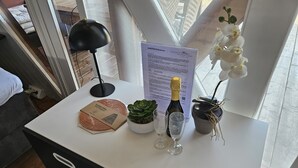 A small table with a bottle of champagne, two glasses, a succulent plant, a decorative item, and a menu. - Mountains&Lakes - Romantika5 Rust (Rust)