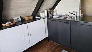 A modern kitchen with dark cabinets, a wooden ceiling, and a built-in sink. - Mountains&Lakes - Romantika5 Rust (Rust)