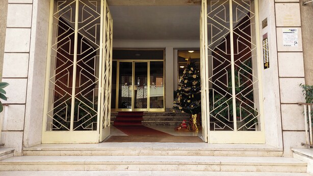 A building entrance with a geometric glass door design, a Christmas tree, and a number '2' sign. - Graceful Apartment near St.Peter - METRO at mt 100 (Roma)
