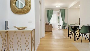 A modern living room with a dining area, featuring a sofa, a dining table with chairs, and a decorative bowl on a console table. - Graceful Apartment near St.Peter - METRO at mt 100 (Roma)