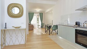 A modern kitchen with a built-in oven, a dining area with a table and chairs, and a living area with a sofa. - Graceful Apartment near St.Peter - METRO at mt 100 (Roma)