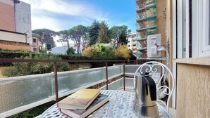 A balcony with a table, books, a kettle, and a view of a river and buildings. - Graceful Apartment near St.Peter - METRO at mt 100 (Roma)