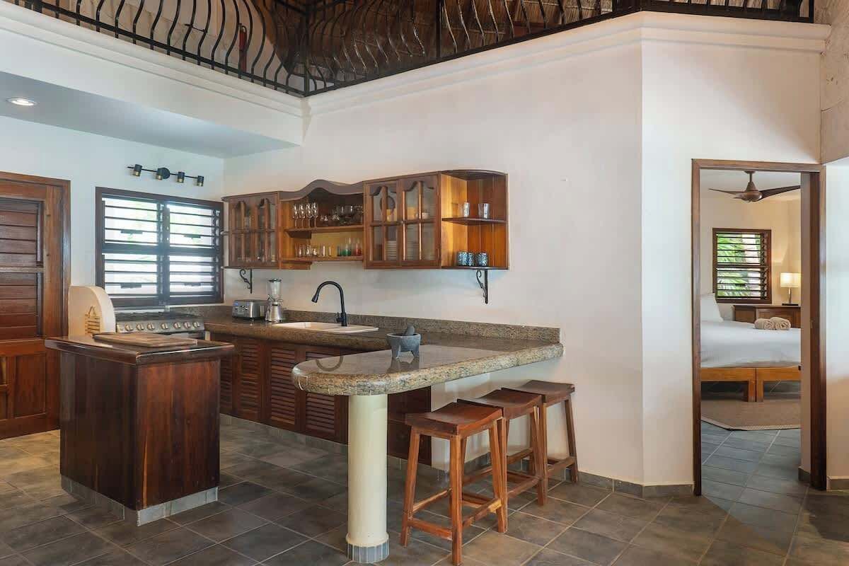 Cozinha com ilha central, armários de madeira e pia embutida.