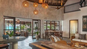 A spacious room with a large dining table, comfortable seating, and a view of the ocean. - La Casa: 3 Bedroom Suite (Tulum)