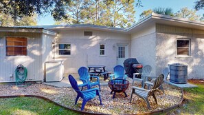 Une maison dotée d’un patio comprenant un barbecue, du mobilier d’extérieur et un foyer.