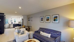 Un espacio habitable compacto con kitchenette, comedor y sofá con cojín estampado.