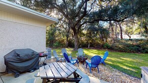 Une terrasse avec une table et des chaises, un barbecue et un espace barbecue couvert.