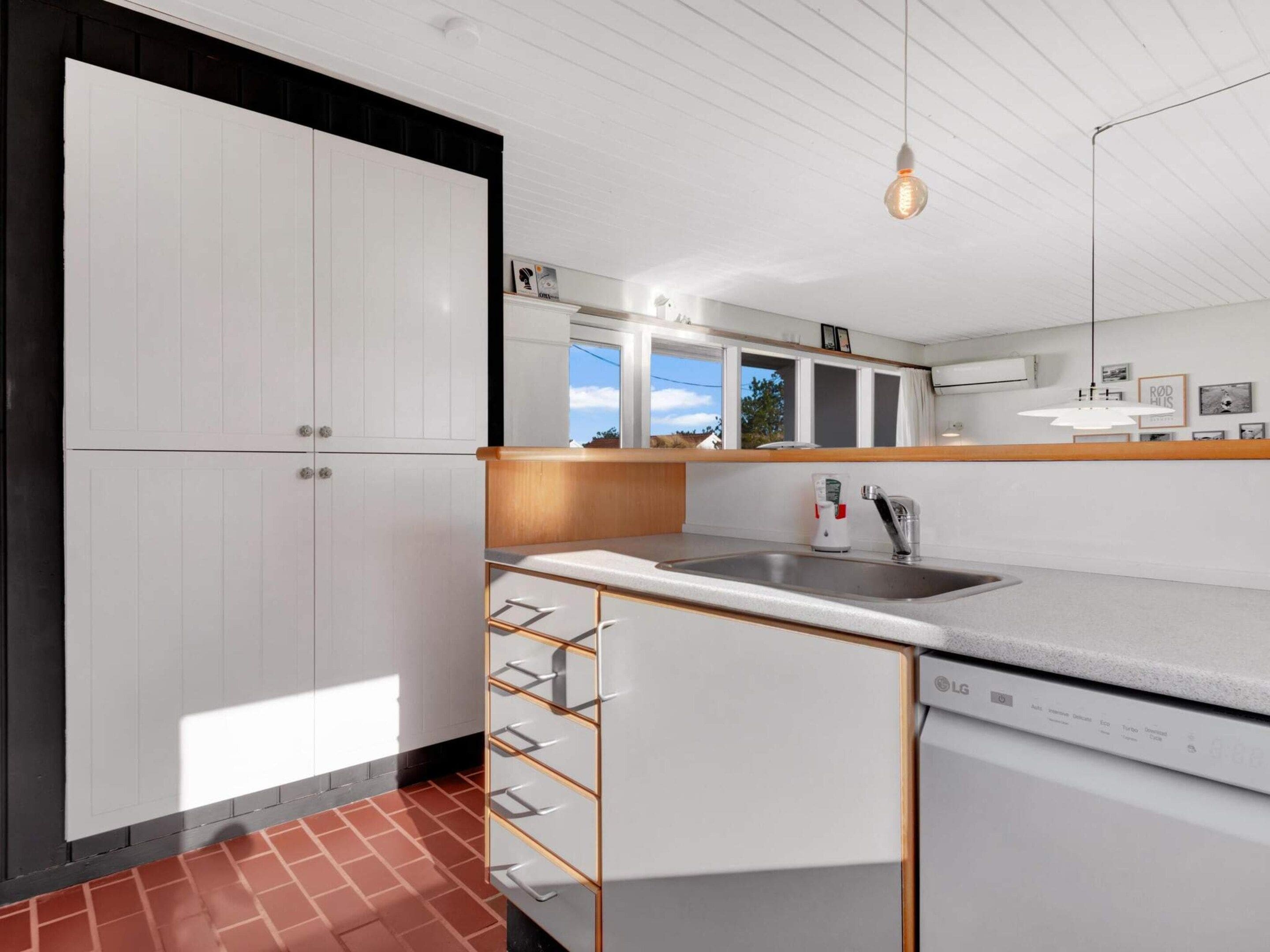 A modern kitchen with white cabinetry, a stainless steel sink, and a built-in dishwasher.