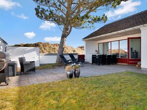 A patio area with outdoor furniture, a grill, and a large tree. - 5 Star Holiday Home in Pandrup (Pandrup)