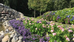 A garden with a stone wall and various flowering plants. - 2 Person Holiday Home in Ringkobing (Ringkobing)
