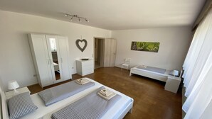 Un dormitorio amplio con una cama grande, un armario, una mesita de noche y una silla.