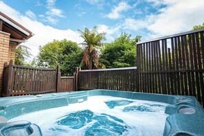A hot tub with a wooden fence and trees in the background. - Highfield on High - Spa Pool, Walk to Redwoods (Rotorua)