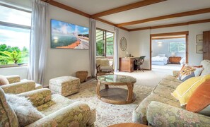 A spacious living room with a large window, a comfortable sofa set, a wooden coffee table, and a painting of a natural landscape. - Highfield on High - Spa Pool, Walk to Redwoods (Rotorua)