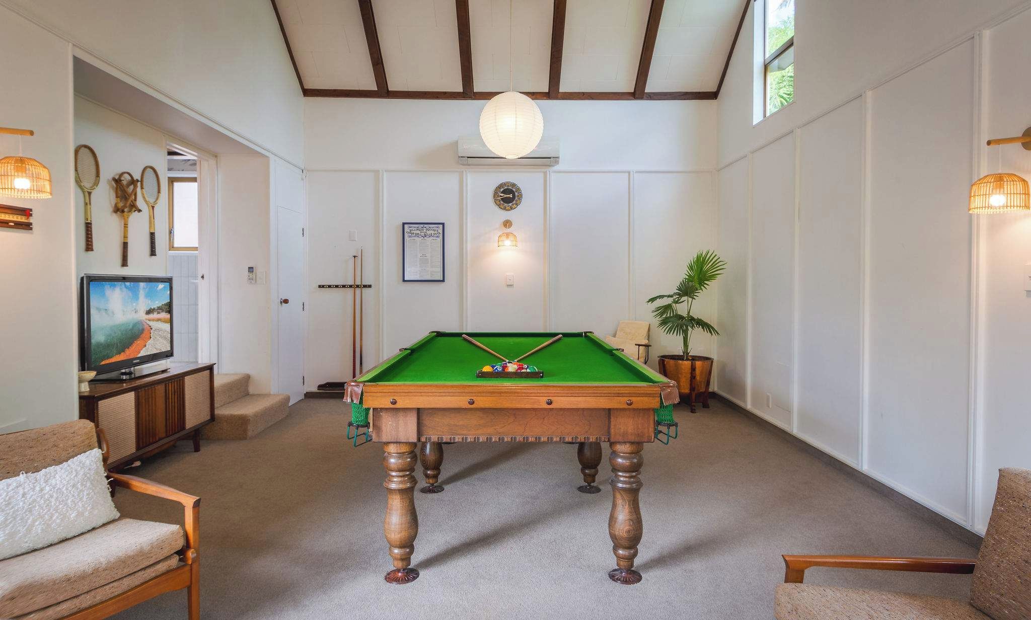 A room with a pool table, a television, and a billiards cue rack.