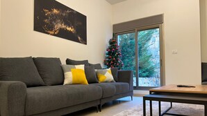 Un soggiorno moderno con un divano grigio, un tavolino da caffè e un albero di Natale.