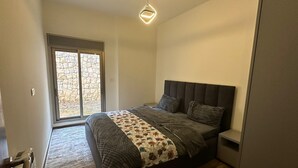 Una camera da letto moderna con un letto grande, una finestra vista pietra e un lampadario geometrico.