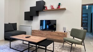 Un soggiorno moderno con divano, tavolino, televisione e camino.