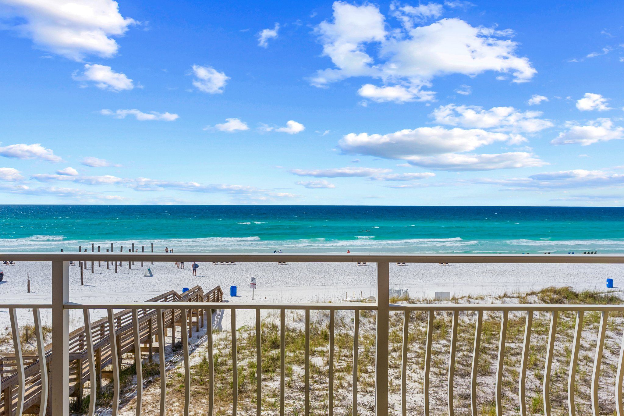A beach view with a wooden deck and a sandy beach.